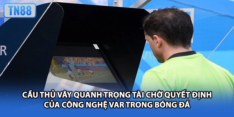 Cầu thủ vây quanh trọng tài chờ quyết định của công nghệ VAR trong bóng đá